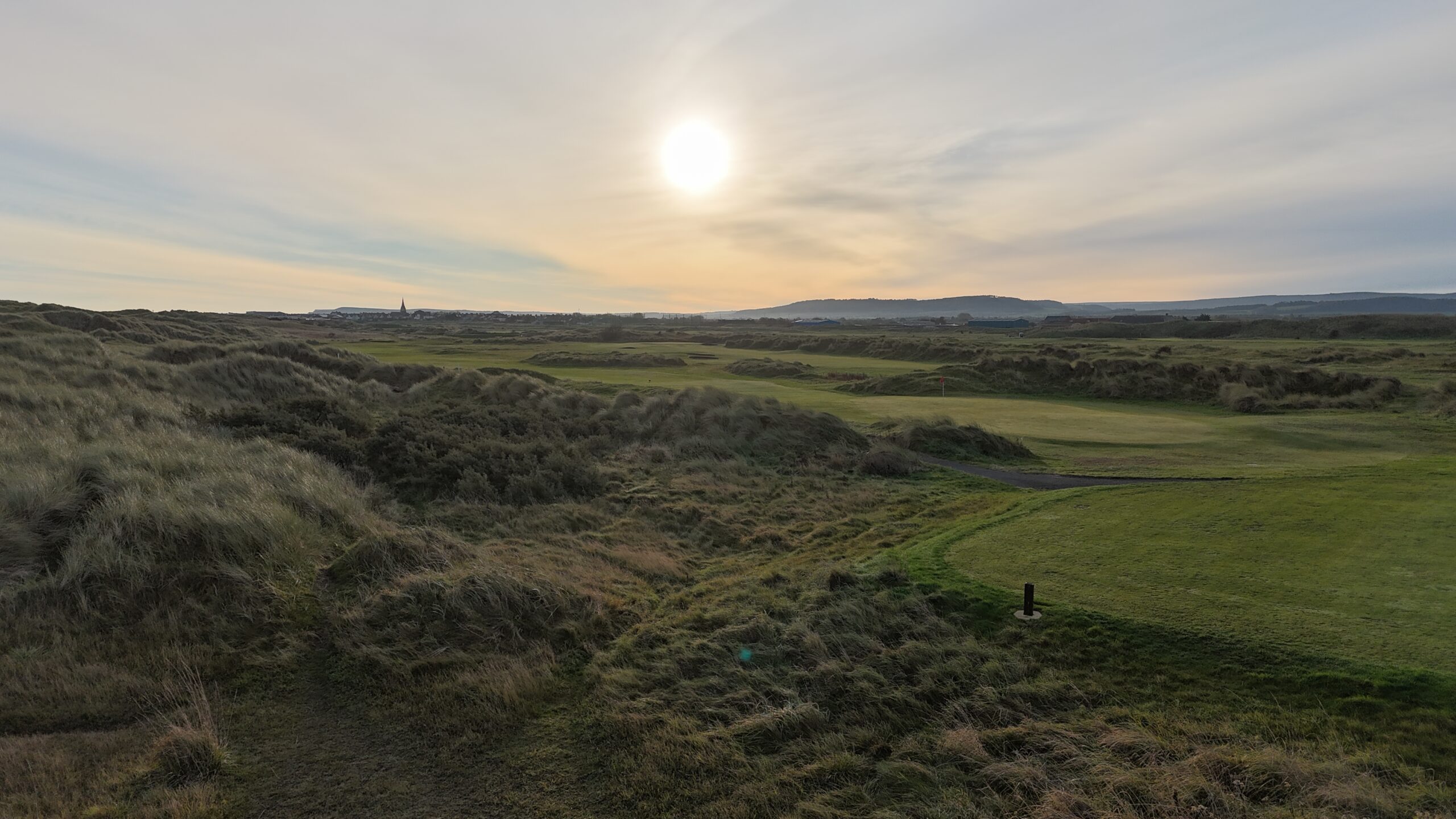 Cleveland Golf Club's links course at sunset, with the flag lit by golden-hour light